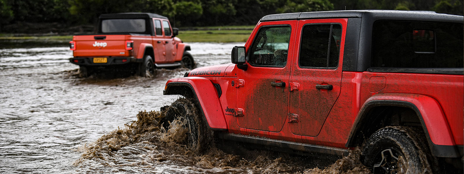 Red Jeep Gladiator driving through water